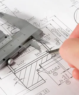 Close-up of a hand marking a technical drawing with a pen