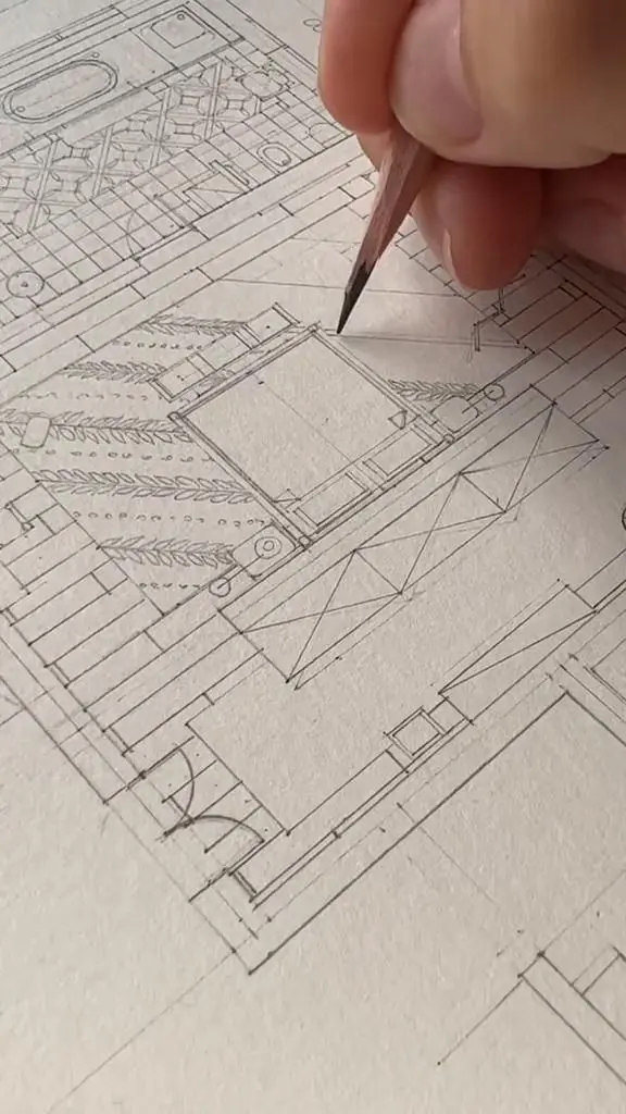 Hand drawing detailed architectural floor plans with a pencil, showing tiled floors, a room layout, and decorative elements.