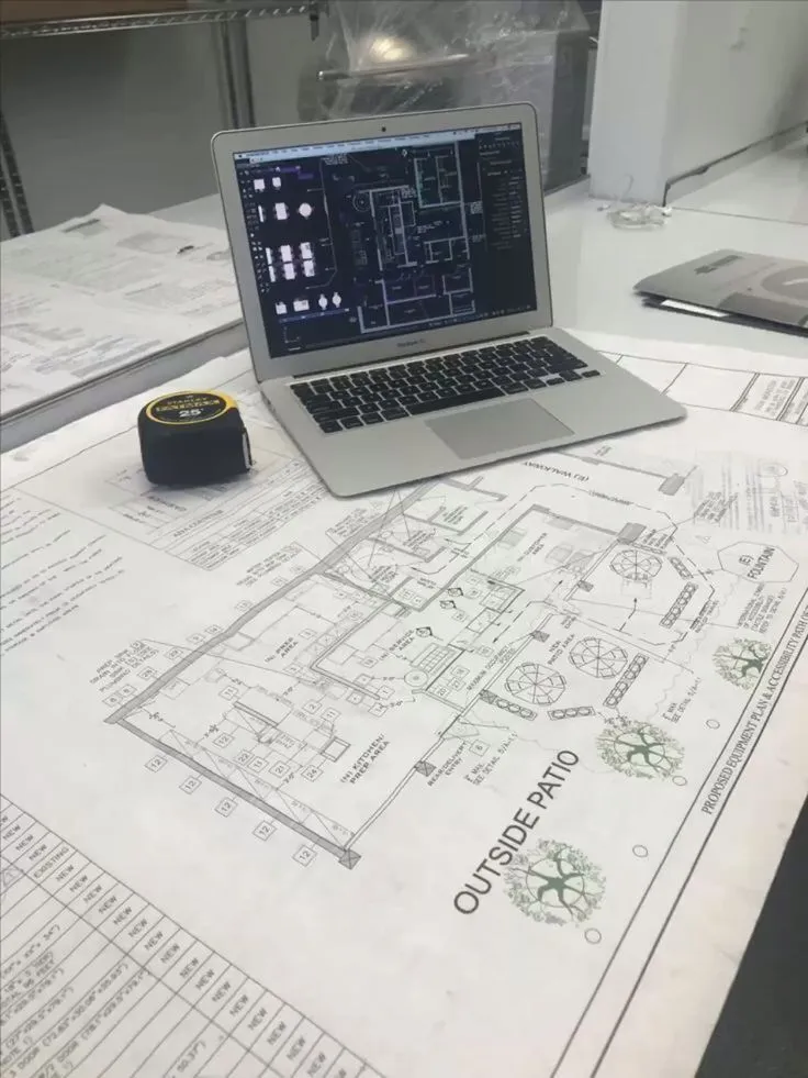 Laptop displaying MEP Shop Drawing Services on top of a printed equipment and accessibility floor plan